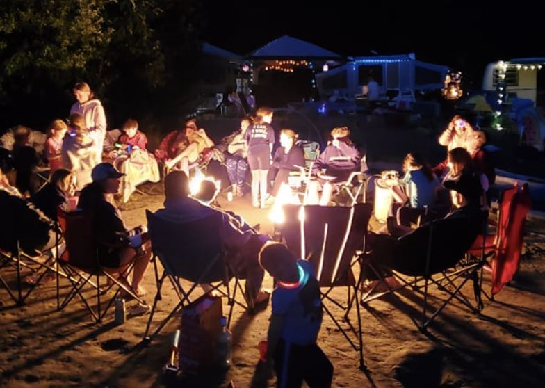 A large group sitting around a campfire at night